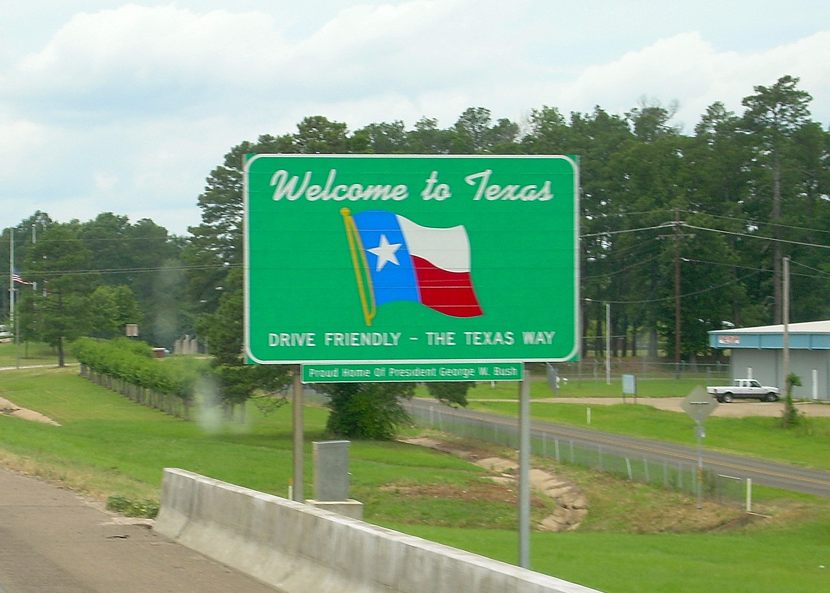 Welcome to Texas signage, flag of Texas, green trees