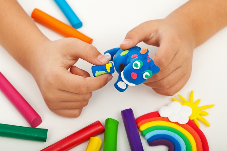 Child creating a blue clay sculpture