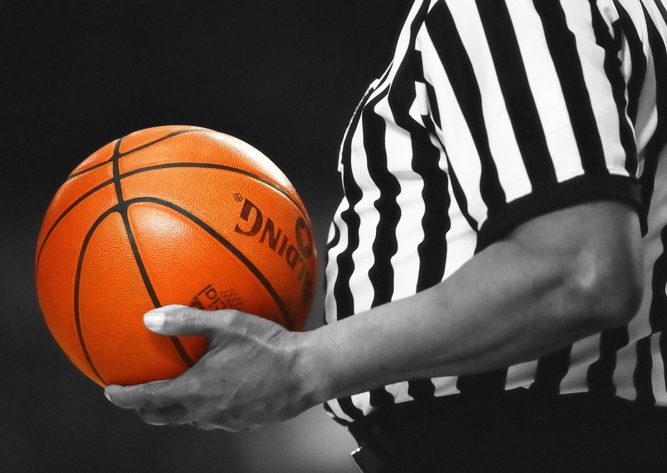 a referee holding an orange basketball ball