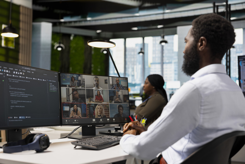 Tech company office coworkers working together via videocall, doing brainstorming on backup solutions to protect against data loss. African American man coding during online teleconference