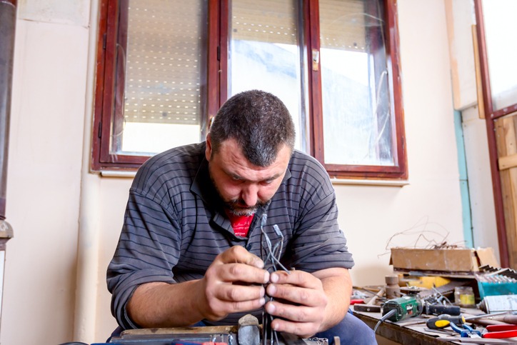 Artist is correcting figurine's posture with his bare hands