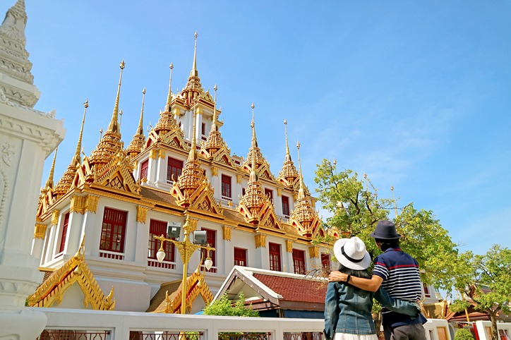 Couple Visiting the Gorgeous Loha Prasat Pagoda Adorned with 37 Golden Spires inside Wat Ratchanatdaram Temple, Historic Temple in Bangkok Old City