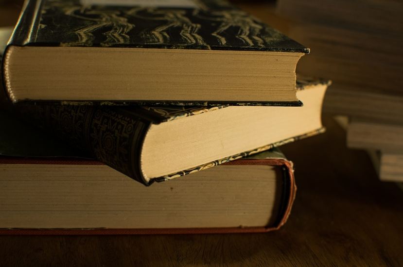 three books stacking up, dark book covers, aged book pages