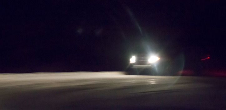 Headlights of a car driving in the dark on snow