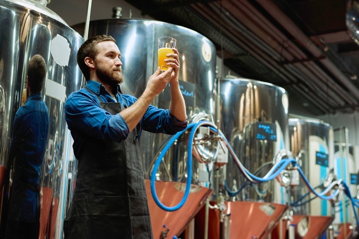 Brewery master with glass of beer in hand evaluating its visual characteristics