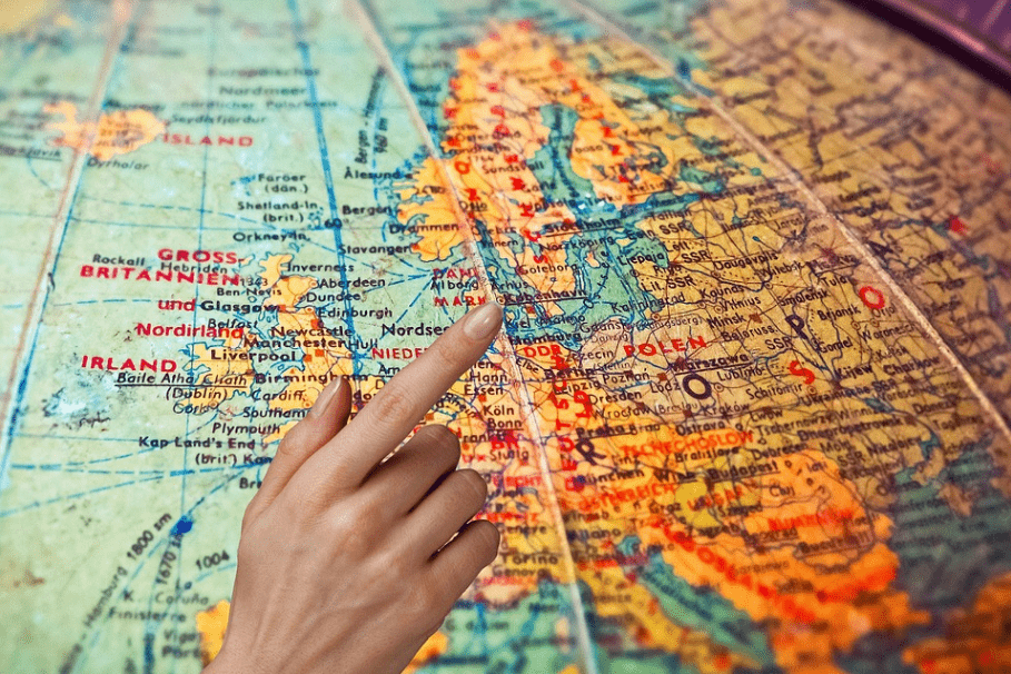 a finger pointing at a certain place within a globe