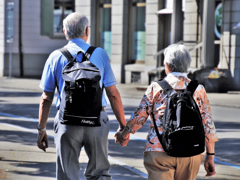 elderly couple going on a walk, backpacks, street, establishments