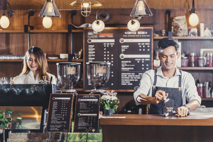 Asian Barista serving a cup of coffee to young customer