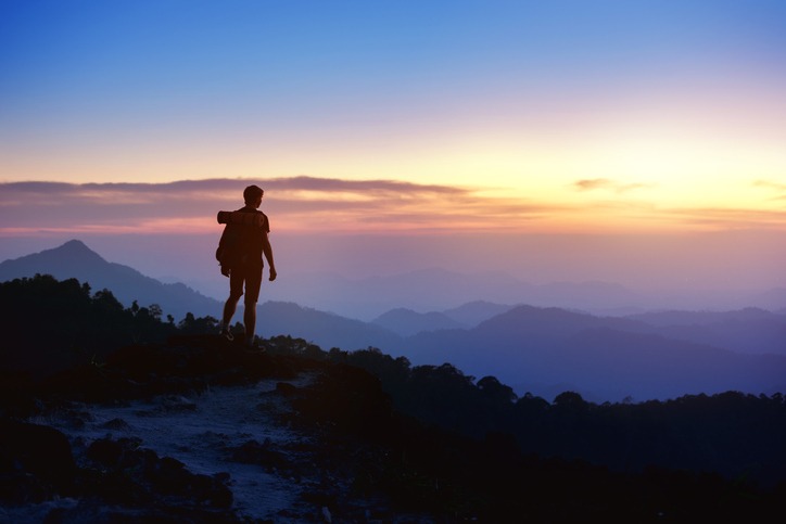 Man's silhouette on sunset mountains backdrop