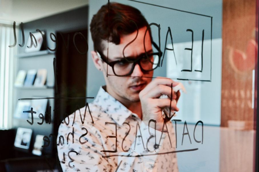 a man writing on a glass using a marker