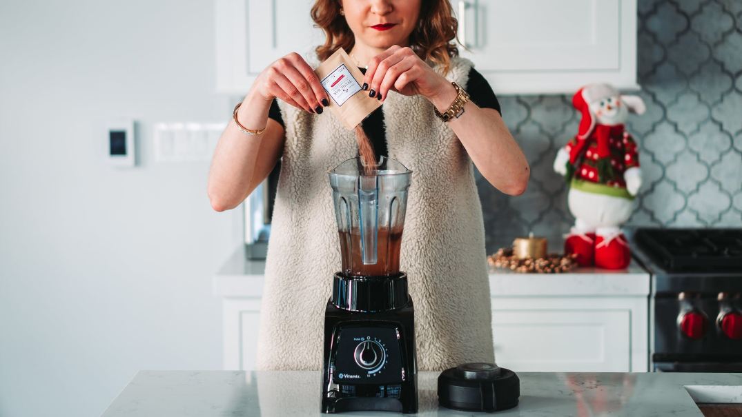 A photo of a woman using a blender