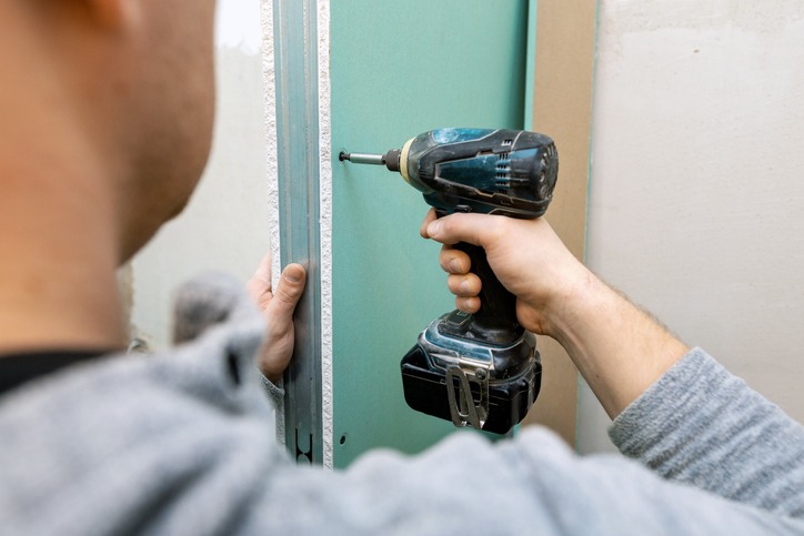 Man installing moisture resistant drywall sheets for bathroom