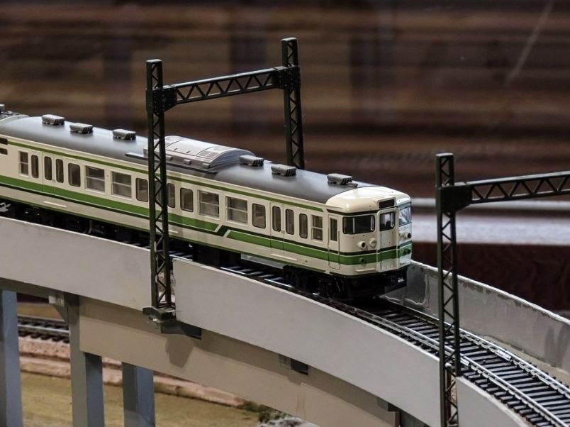 a gray electric train model passing through a railroad model