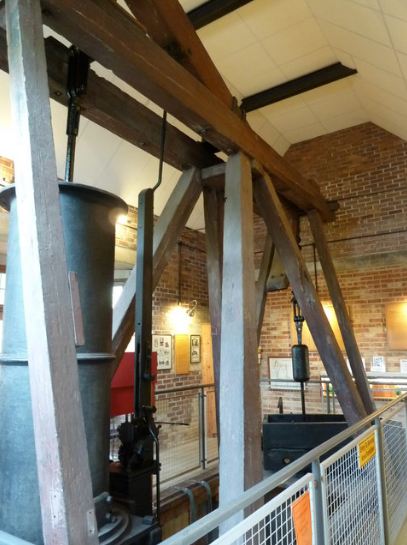 steam engine in Dartmouth, orange bricked walls, large machines hanging on a wooden stand