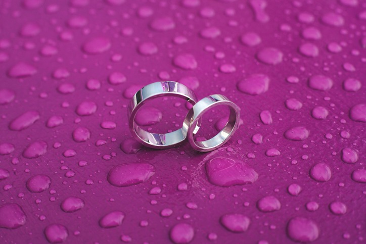 Wedding rings on a pink surface in the rain