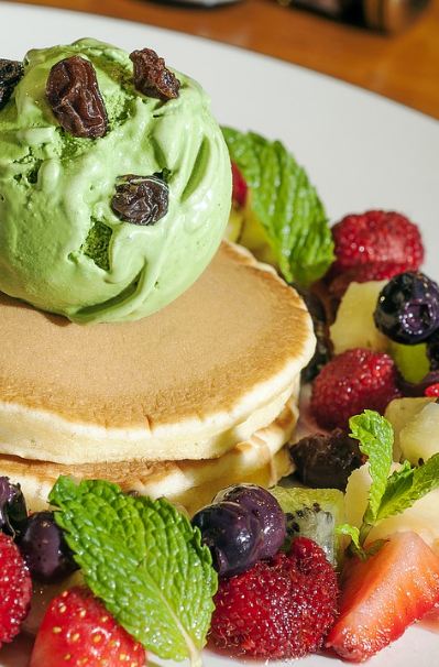 stacked pancakes, pancake topped with ice cream, fruits, mint leaves, raisins